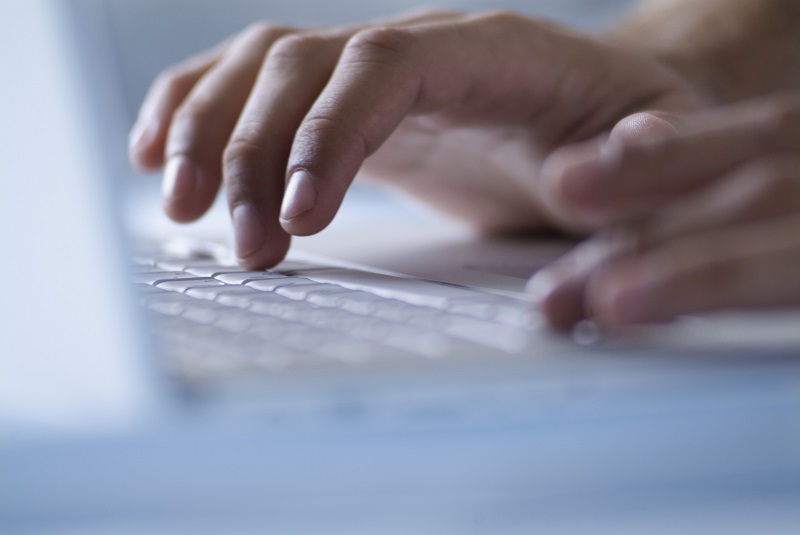 Close-up of fingers typing on a laptop