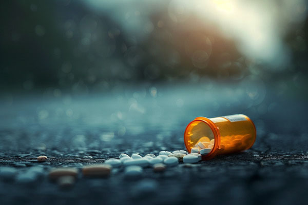 Pill bottle laying on its side with pills spilling out