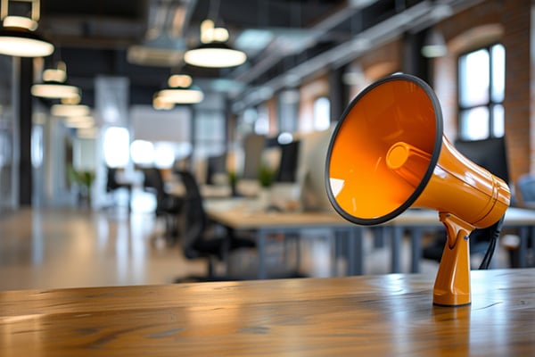 An orange megaphone sitting on an office desk.