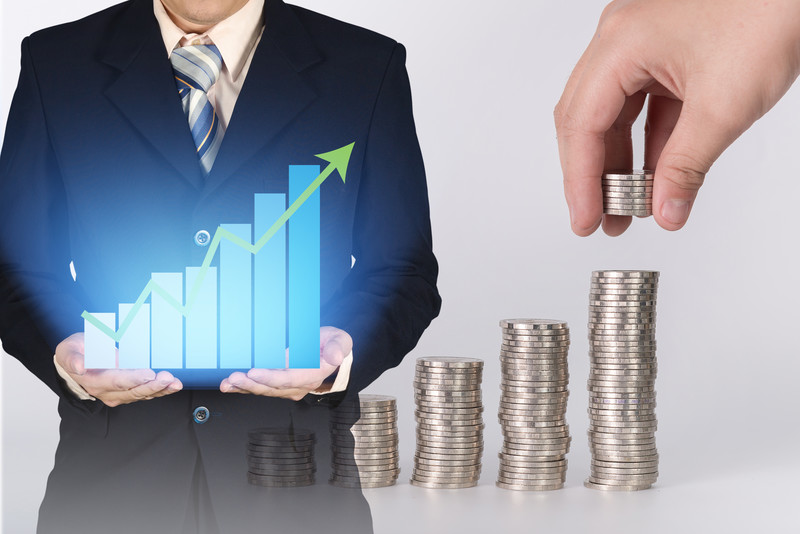 Businessman holding upward graph with coins