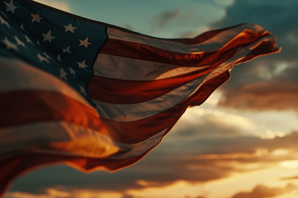 A close-up image of the American flag flying in the wind at sunrise