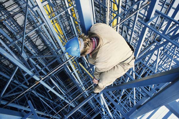 A construction worker looking down from scaffolding