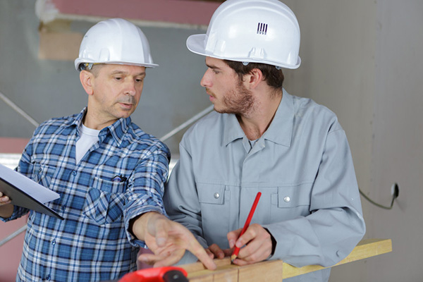 Two construction workers talking and pointing at board