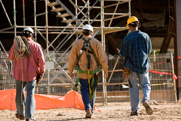 Three construction workers walking together on a construction site