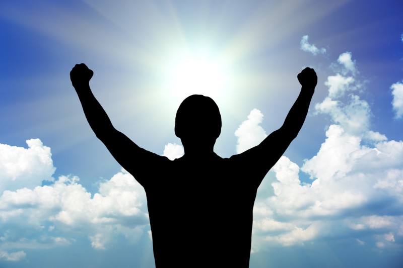 Person celebrating with arms in the air and a blue cloudy sky