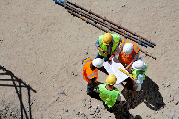 A circle of construction workers looking at plans