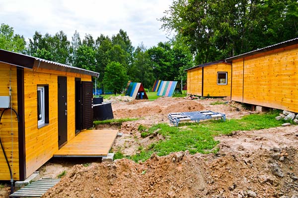 Prefabricated buildings sitting on concrete blocks on a roughly graded lot