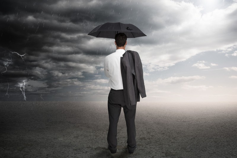 Businessman holding umbrella watching storm