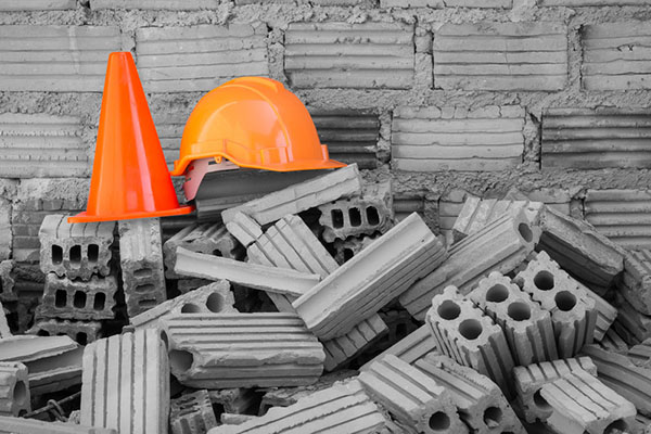 A hard hat and an orange cone on top of a pile of cinder blocks