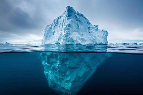 A large iceberg with the top half visible above water and the bottom half visible below water