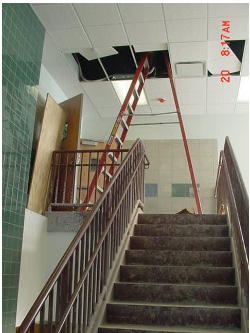 Stairs in a commercial building with a ladder above them to fix ceiling tiles