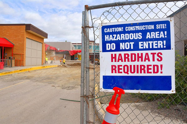 Hard hats required sign on a fence