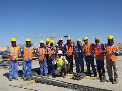 A group of construction workers in hard hats and orange vests giving thumbs up