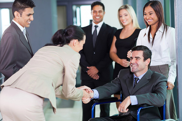 Business people shaking hands of one in a wheelchair