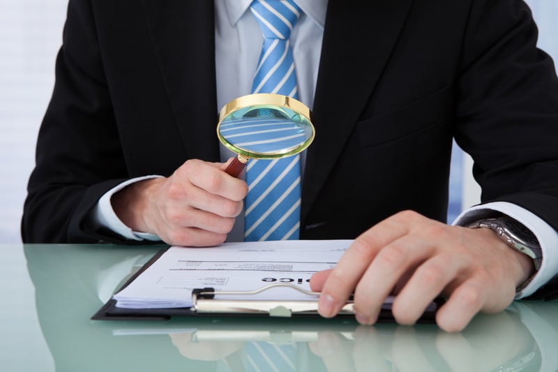 Businessman using magnifying glass on a report