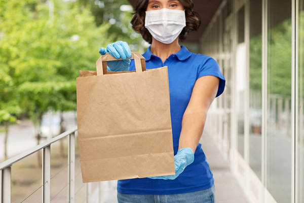 Woman wearing a medical mask and gloves making a delivery