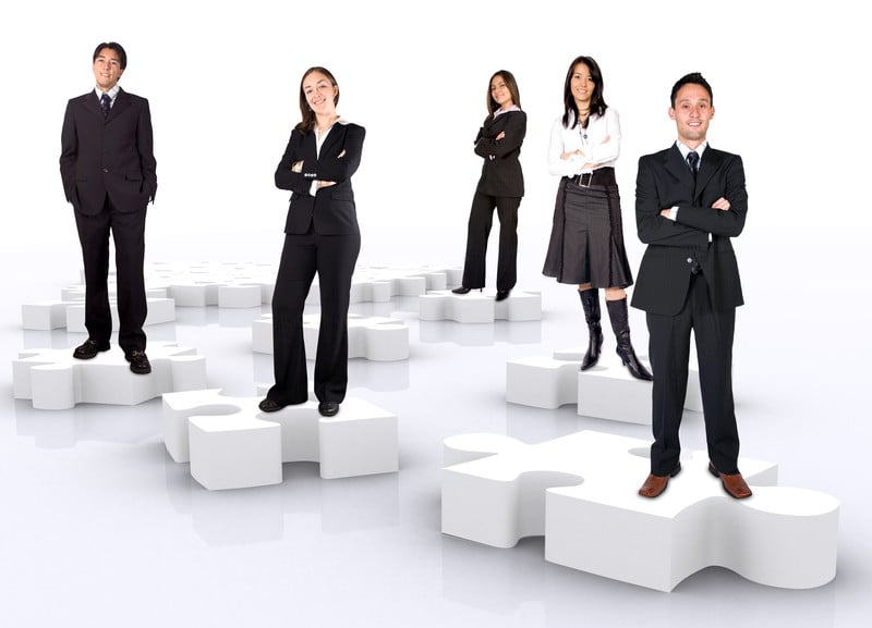 Businesspeople standing on puzzle pieces
