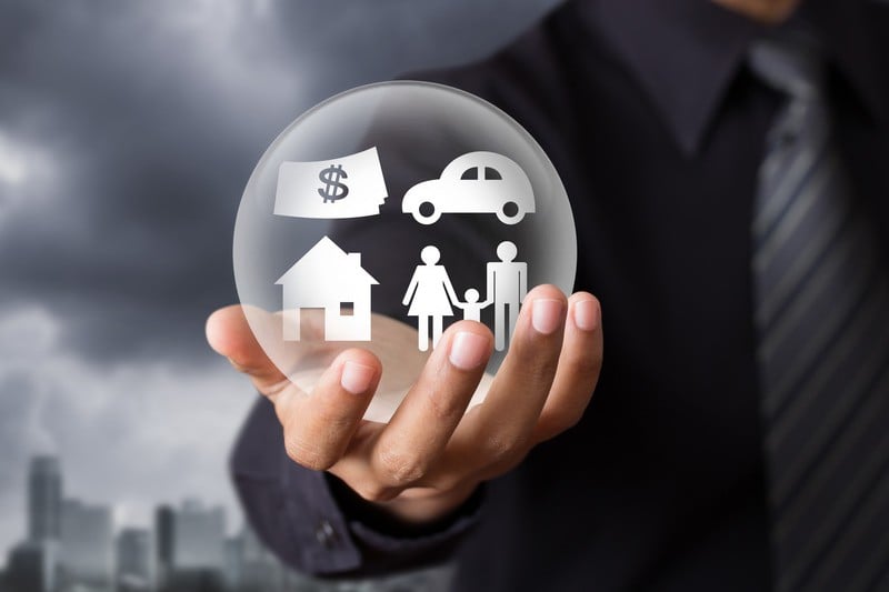 Man in suit holding clear ball with icons inside for family, home, car, and money