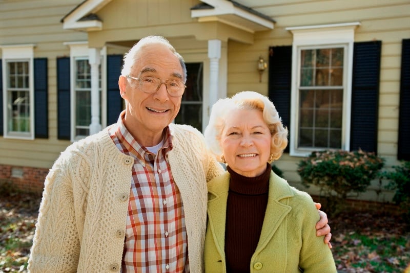 Older couple standing in front of a house