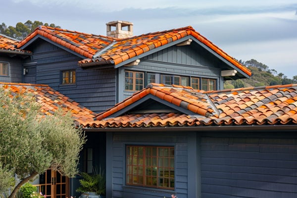 A close-up image of a grayish blue home with a brown roof