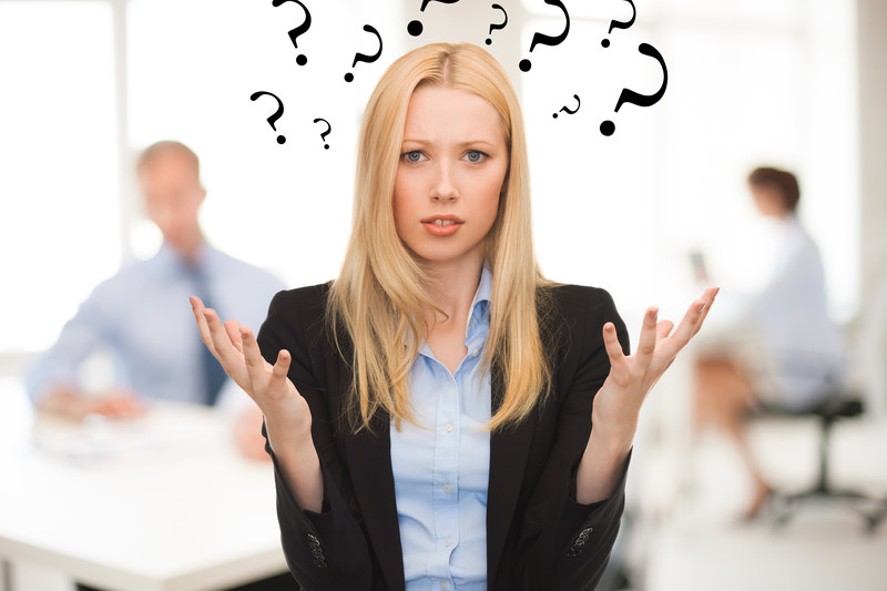 Confused looking businesswoman with question marks around her head