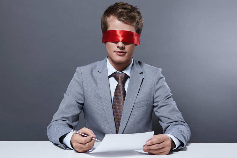 Businessman wearing blindfold holding pen and paper