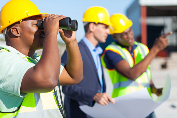 Workers looking at construction site with binoculars