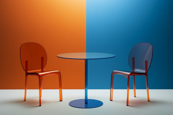 A table sits between an orange chair against an orange wall and a blue chair against a blue wall