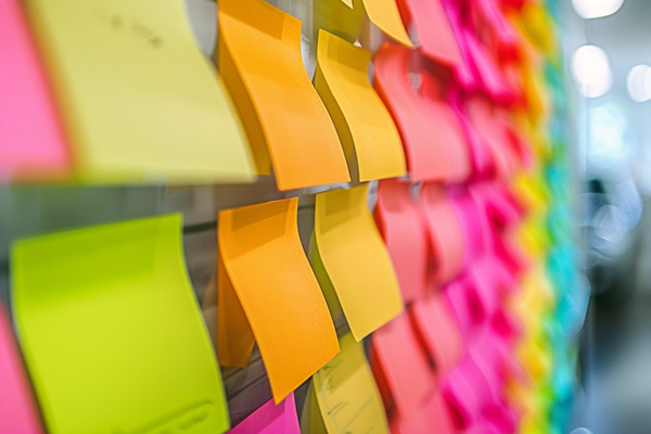 Multi-colored post-it notes in rows on an office whiteboard.
