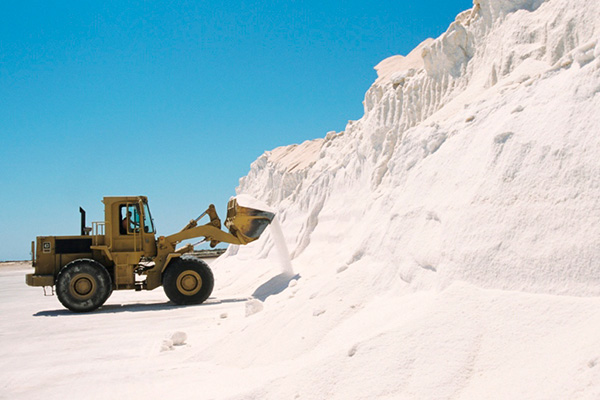 Front-end loader picking up white sand