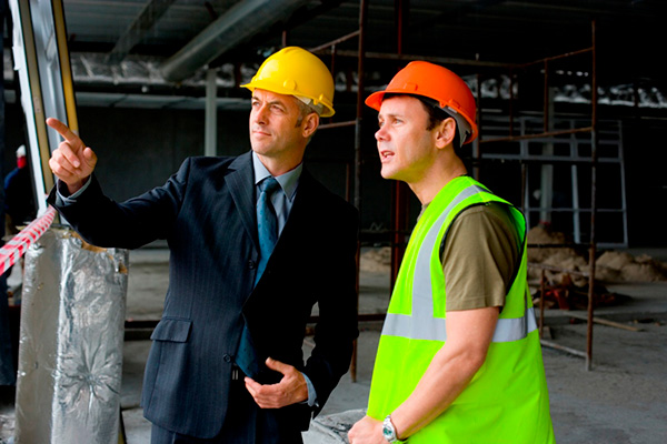 Businessman pointing out something to construction worker