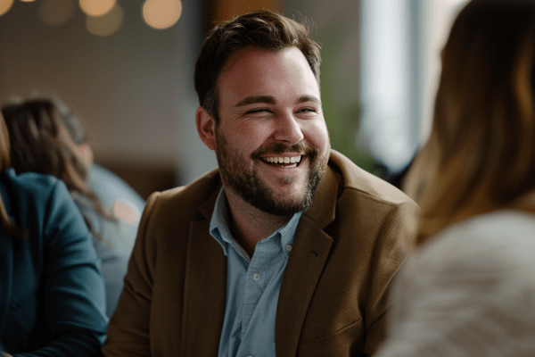 A businessman laughs while talking with coworkers in the office