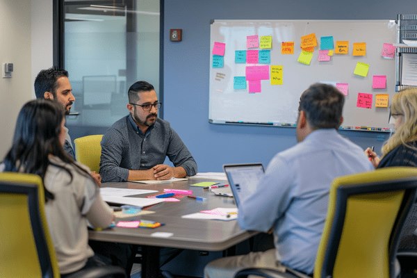 Business professionals work in a meeting room with colorful post-it notes on the whiteboard