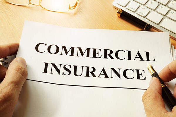 A hand holding a commercial insurance form