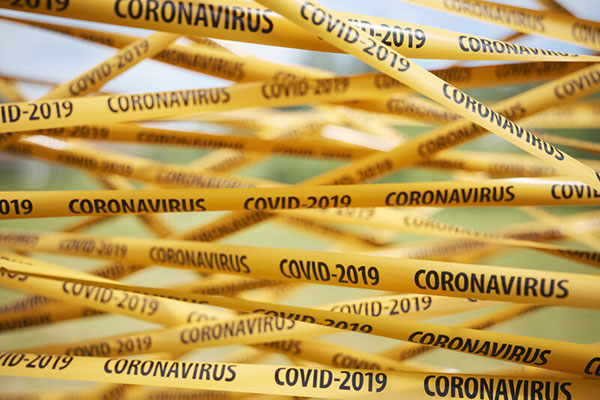 Lots of crisscrossing yellow tape with coronavirus and COVID-19 written on them