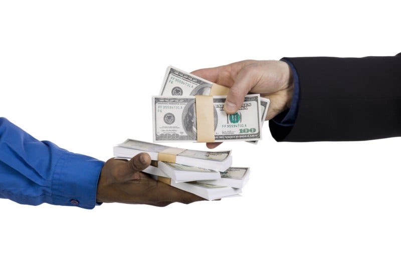 Businessperson putting money in another businessperson's hands