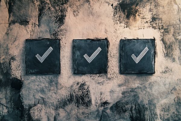 three boxes with checkmarks on a beige and black smudged wall