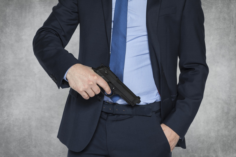 Businessman pulling a pistol out of his waistband