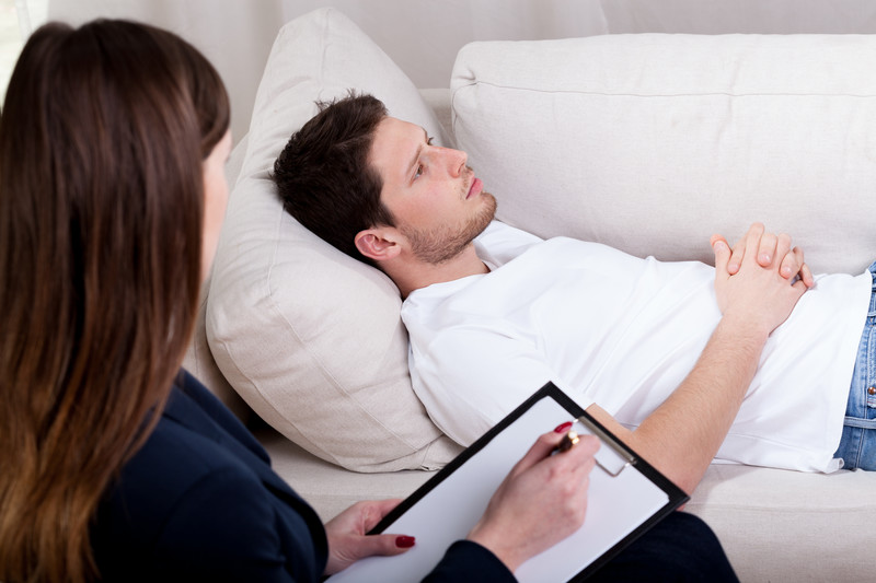 Young adult patient lying on a couch with a therapist