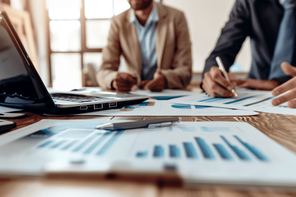 Charts and graphs on an office table while coworkers review them and talk