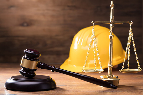Judge's gavel with a law scale and a yellow construction hard hat