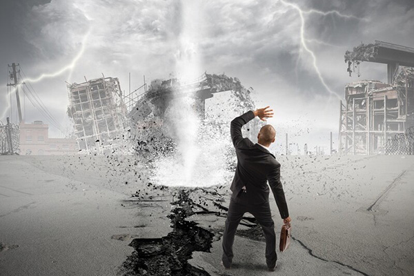 Businessman standing in front of a tornado and building wreckage