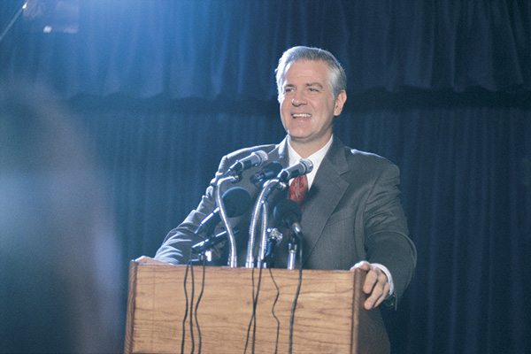 Man in suit behind podium making a speech