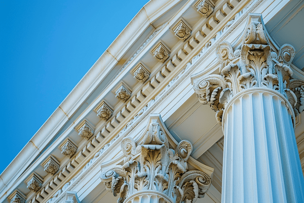 The top of columns and the roof of a courthouse under a blue sky