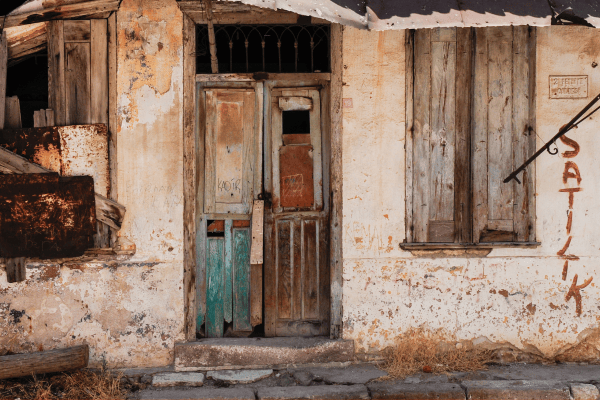 A boarded-up and abandoned house with graffiti on its wall  