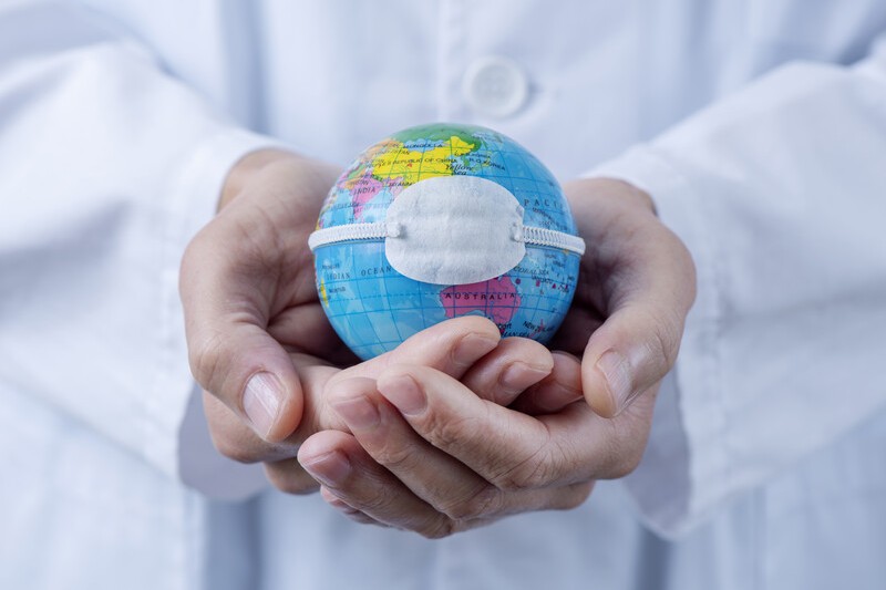 Doctor holding small globe wearing a medical mask